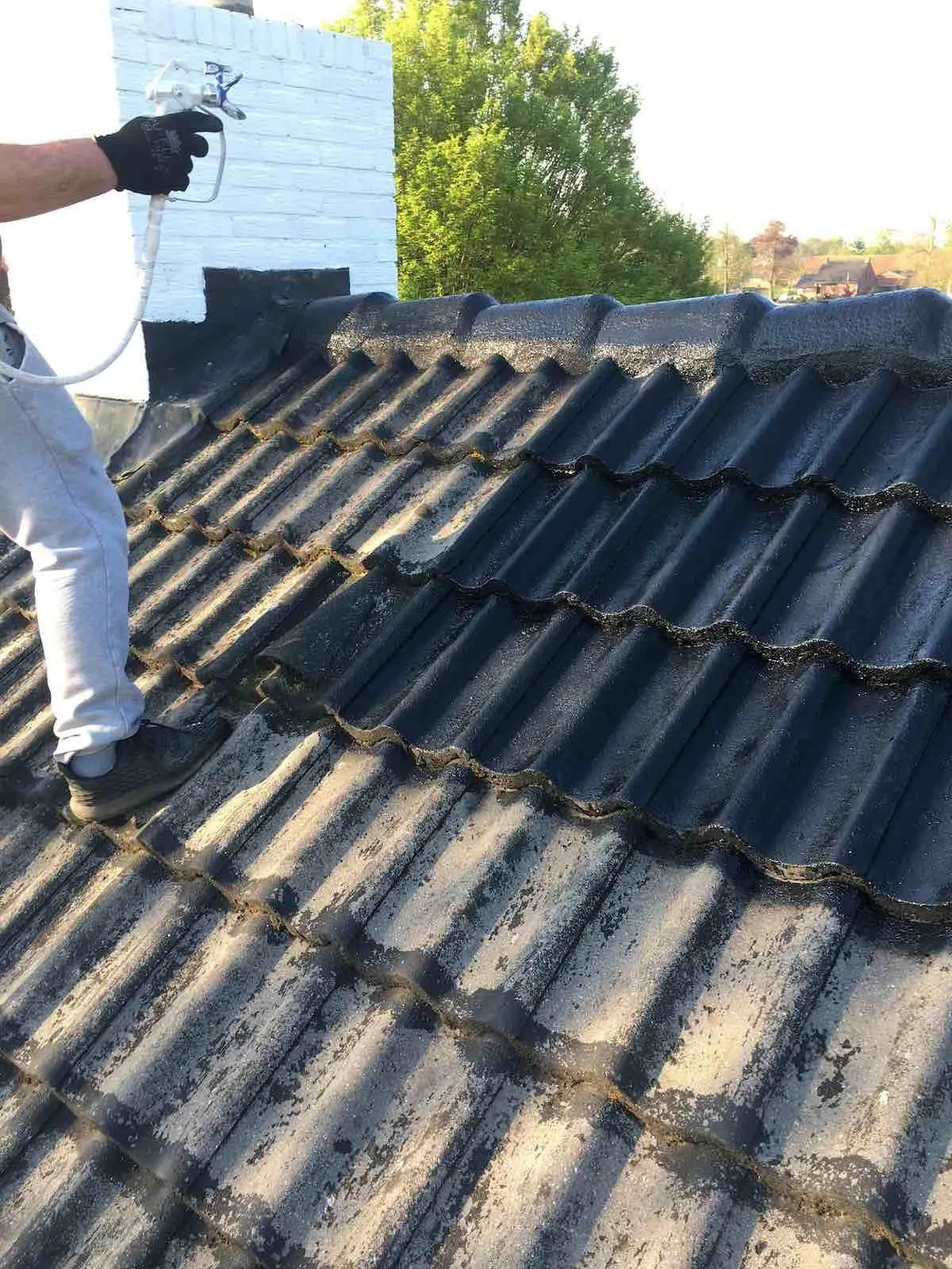 Dakdekker brengt coating aan op een donker pannendak
