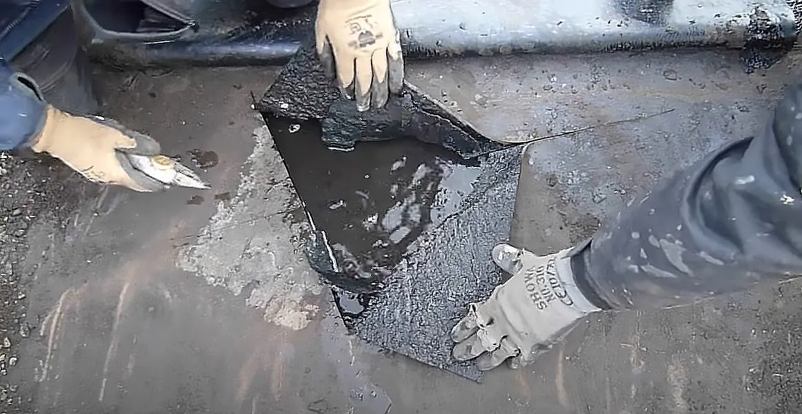 Dakdekker herstelt een scheur in de bitumen dakbedekking