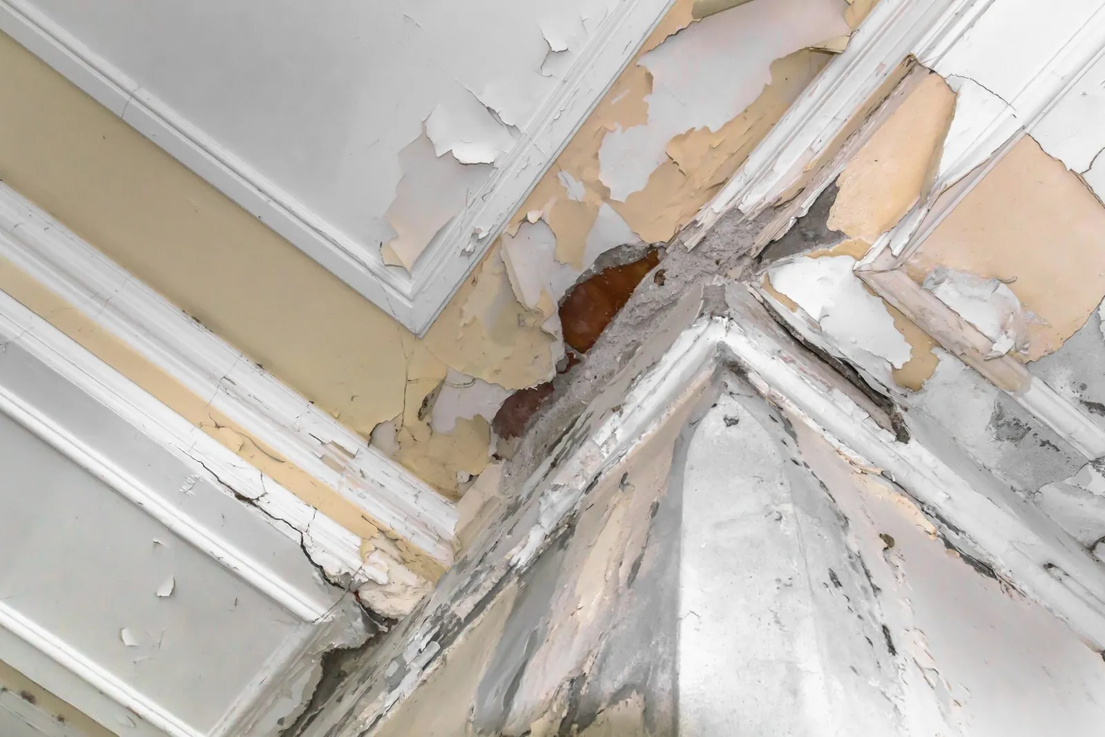 Afgebladderde verf en waterschade in de hoek van een plafond