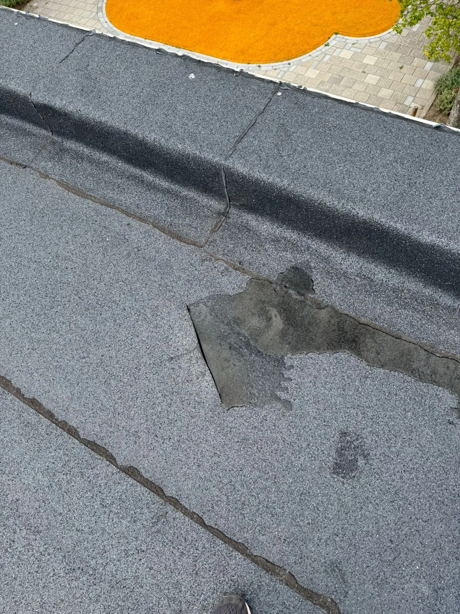 Plas water op een plat dak met een reparatiestuk in de dakbedekking