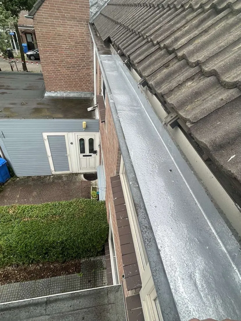 Zinken dakgoot langs een pannendak, van bovenaf bekeken