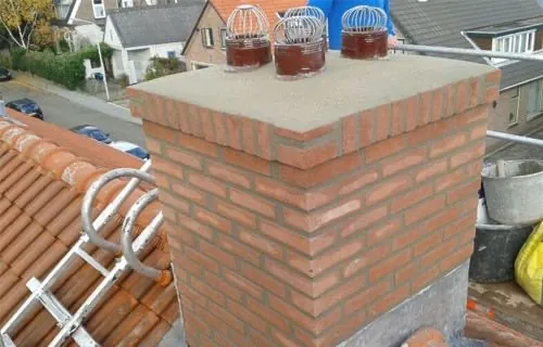 Gemetselde schoorsteen met een nieuwe afdekplaat en kappen